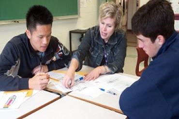 A teacher and her students look at a textbook